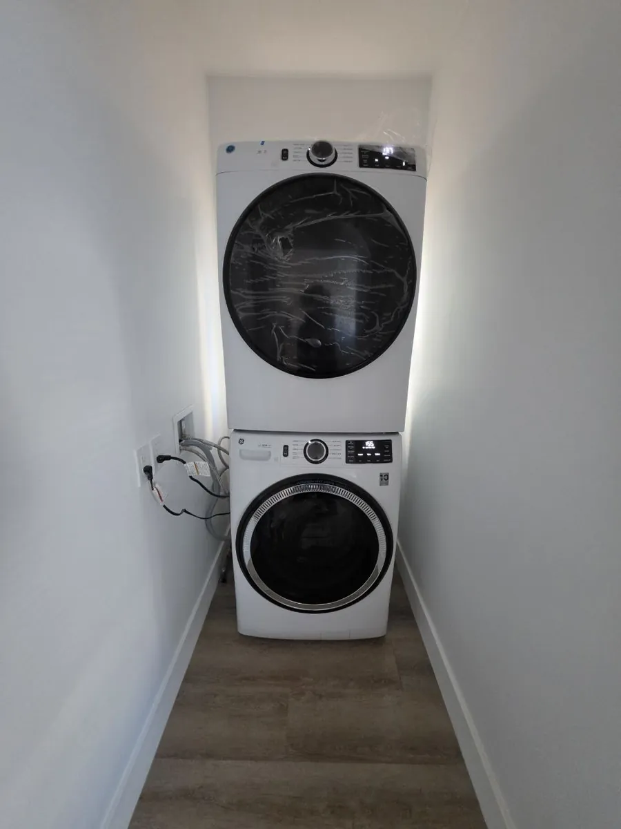 New stacked washer and gas dryer in a renovated apartment laundry closet with a recessed washer box