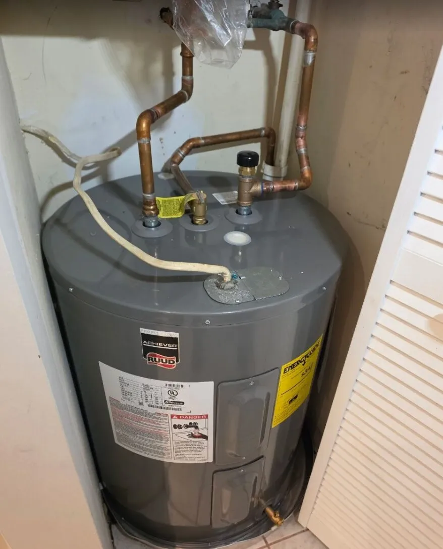 Old leaking electric water heater in a home closet before replacement