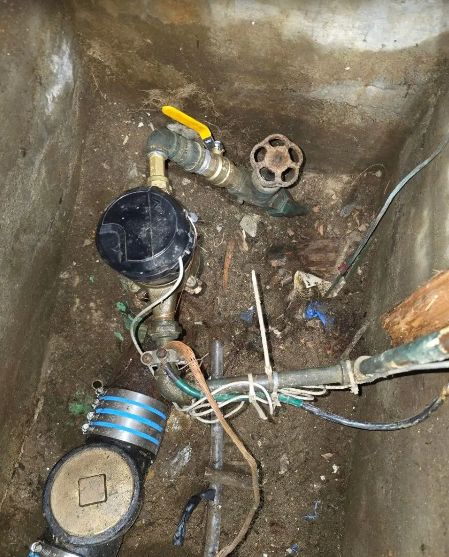 Water meter pit with a failed service shutoff valve and corroded fittings before repair