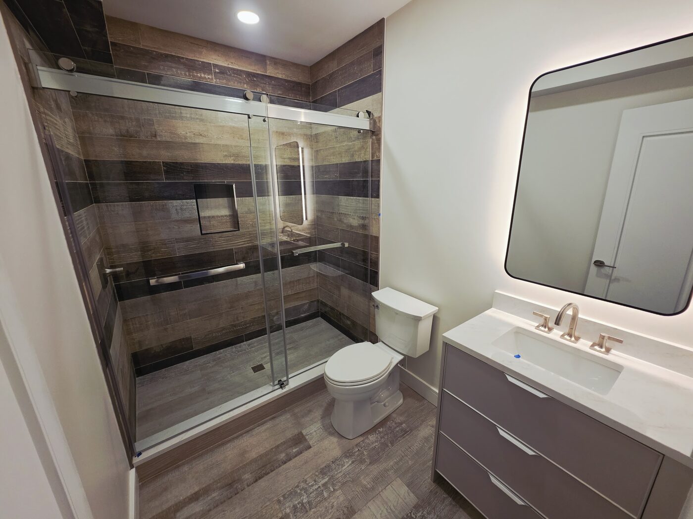 Bathroom remodel with wood-look porcelain tile, frameless glass shower and floating vanity