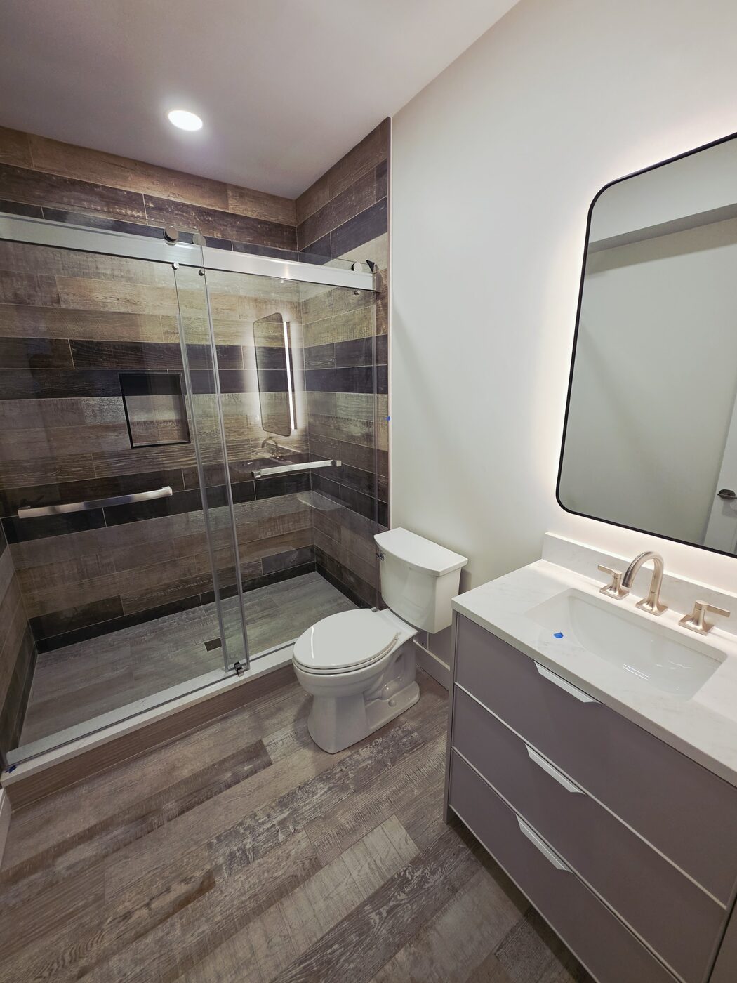 Finished bathroom remodel with wood-look tile, floating vanity and frameless glass shower