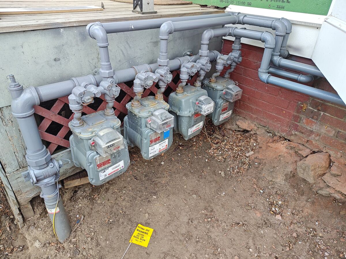 Bank of new gas meters and gas piping installed for a multi-unit building