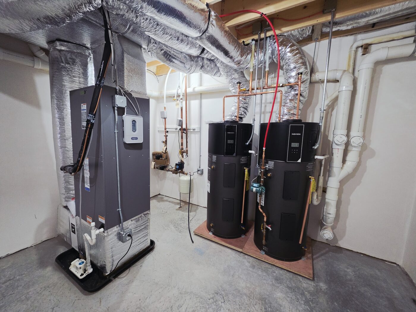 Two heat pump water heaters installed side by side in a basement, eligible for Mass Save rebates