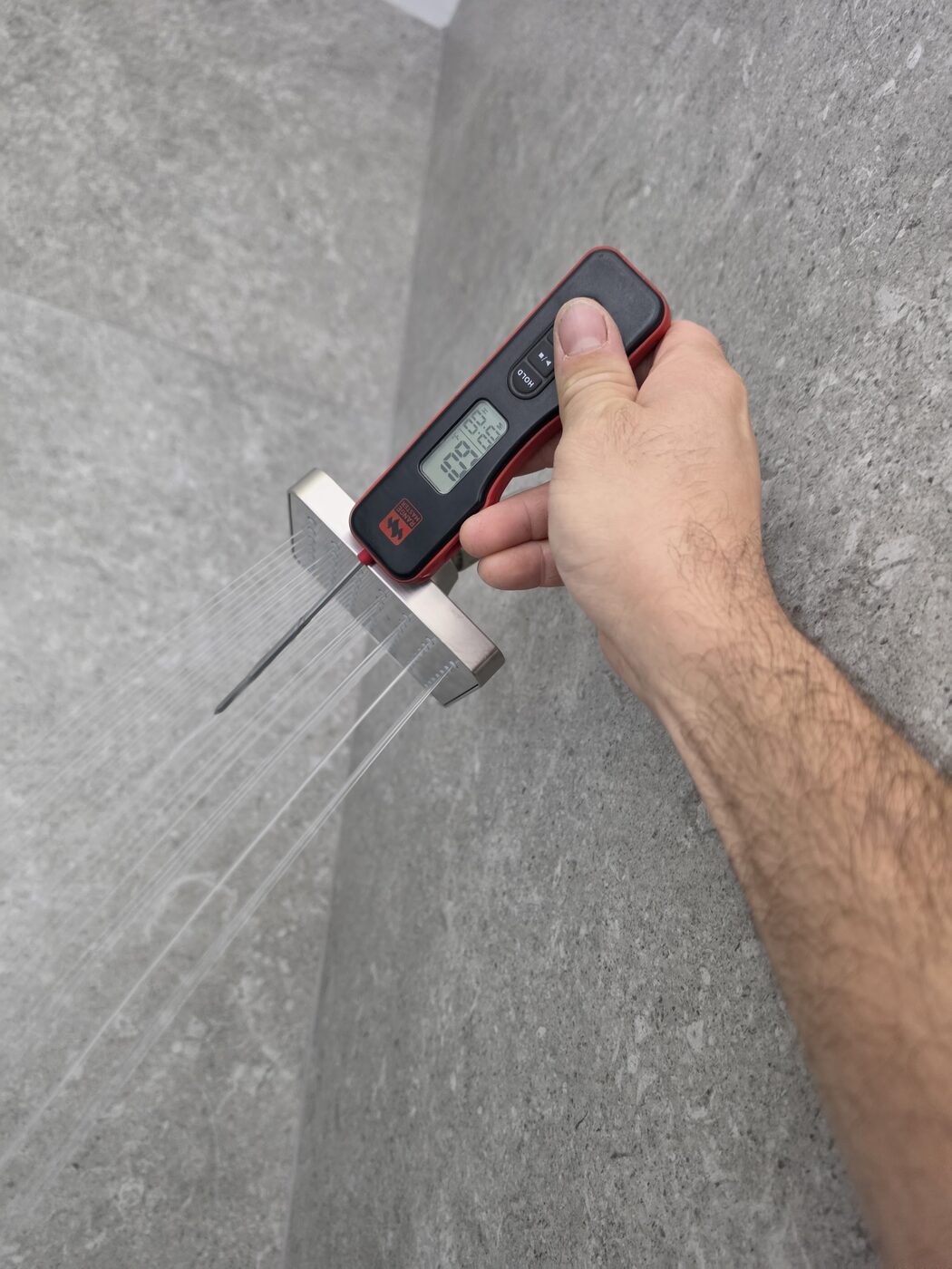 IS Plumbing checking hot water delivery temperature with a digital thermometer before leaving a job
