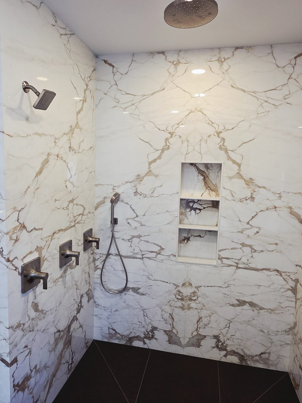 Marble walk-in shower with a rain head, hand shower and recessed niche