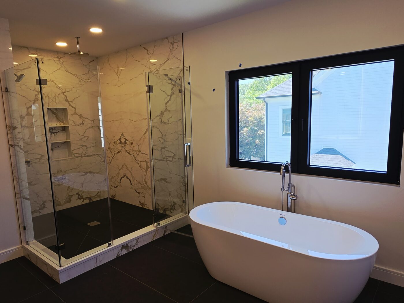 Master bathroom with a freestanding soaking tub, floor-mounted tub filler and marble walk-in shower