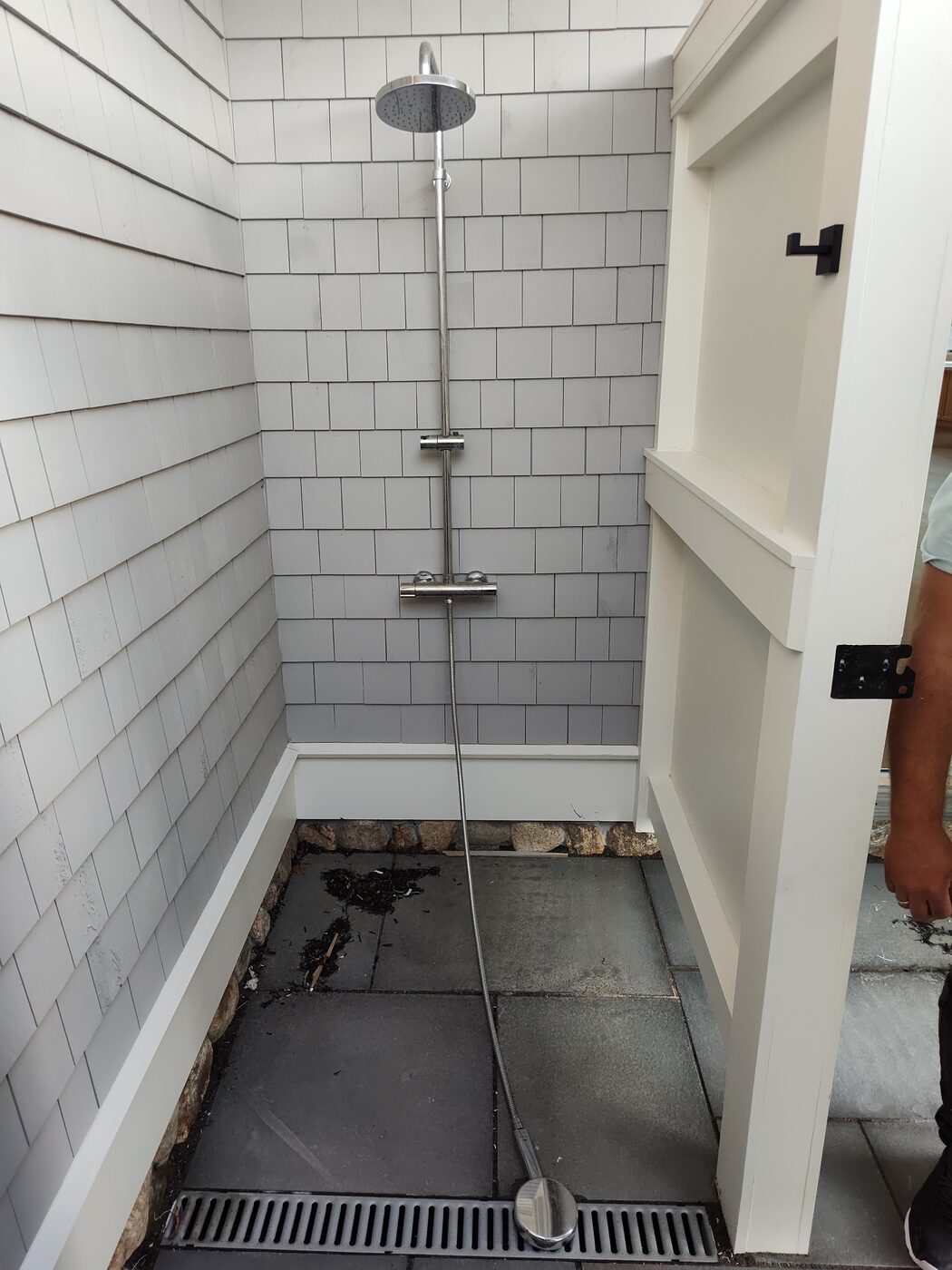 Outdoor shower with a rain head and mixing valve built into a cedar-shingle wall