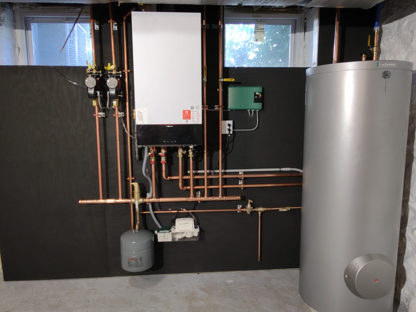 Tankless condensing boiler with a copper piping manifold and water heater tank installed by IS Plumbing