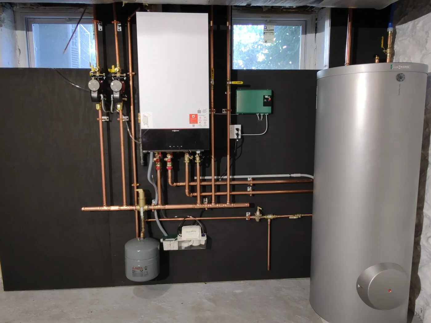 Tankless condensing boiler with a copper manifold and storage tank installed by IS Plumbing