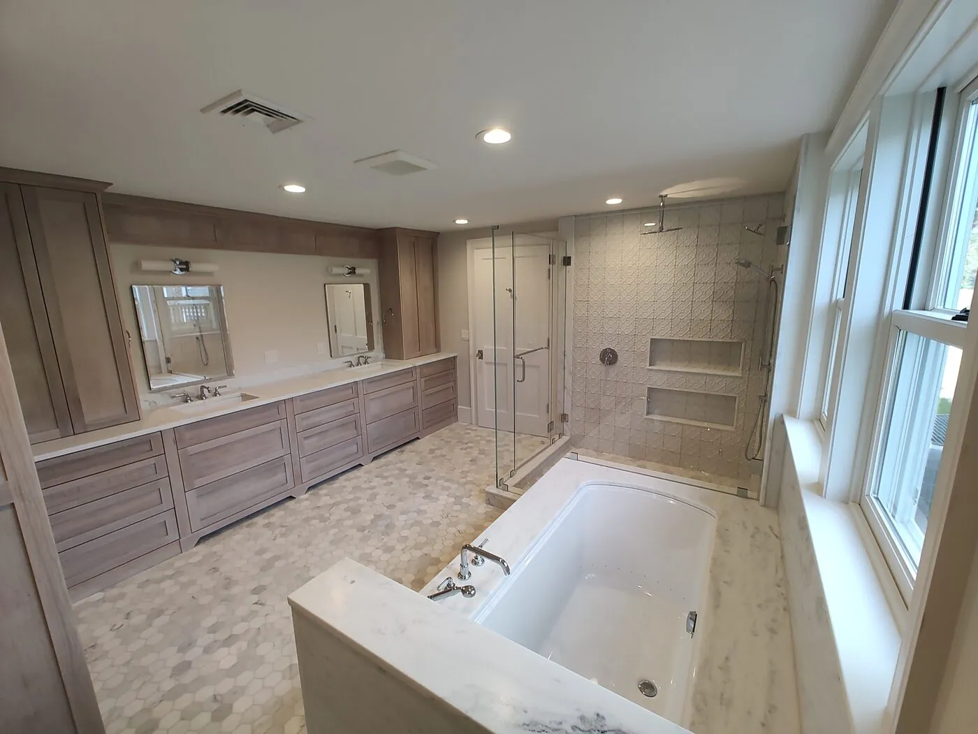 Renovated master bathroom with a double vanity, soaking tub and glass walk-in shower by IS Plumbing