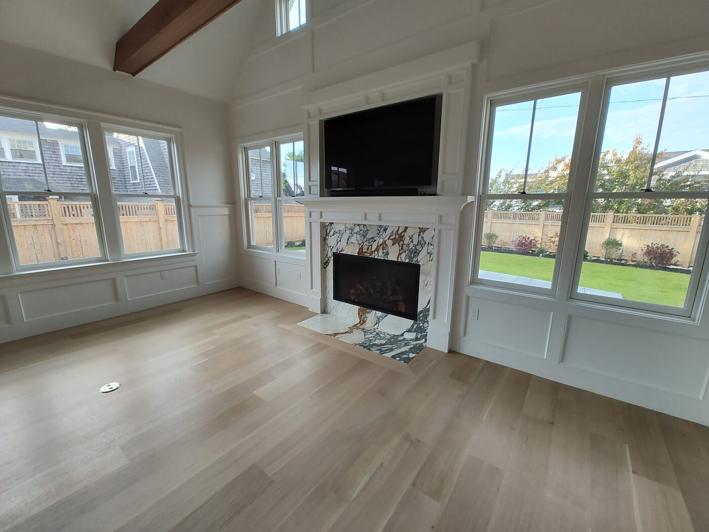Living room remodel with a fireplace, hardwood floors and large windows