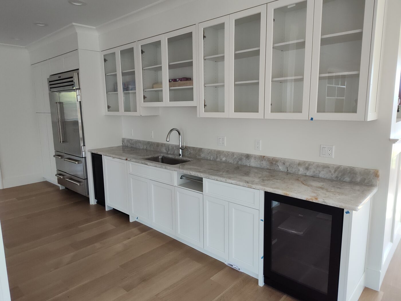 Remodeled kitchen with white cabinetry, stone countertops and a beverage fridge
