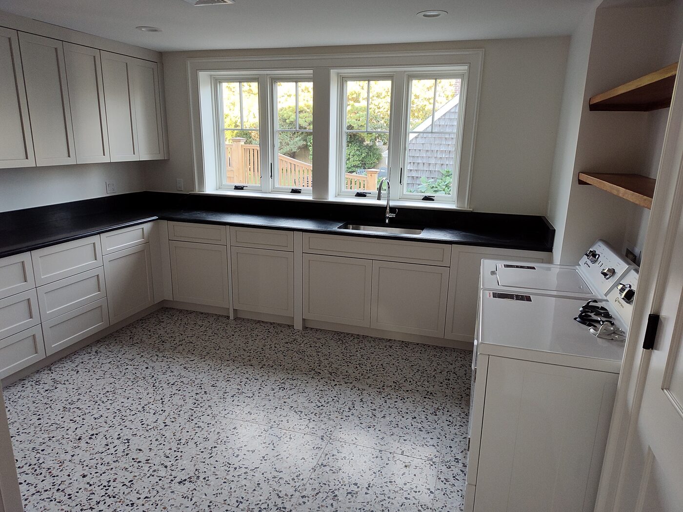 Kitchen with white cabinets, dark stone countertops and bright windows