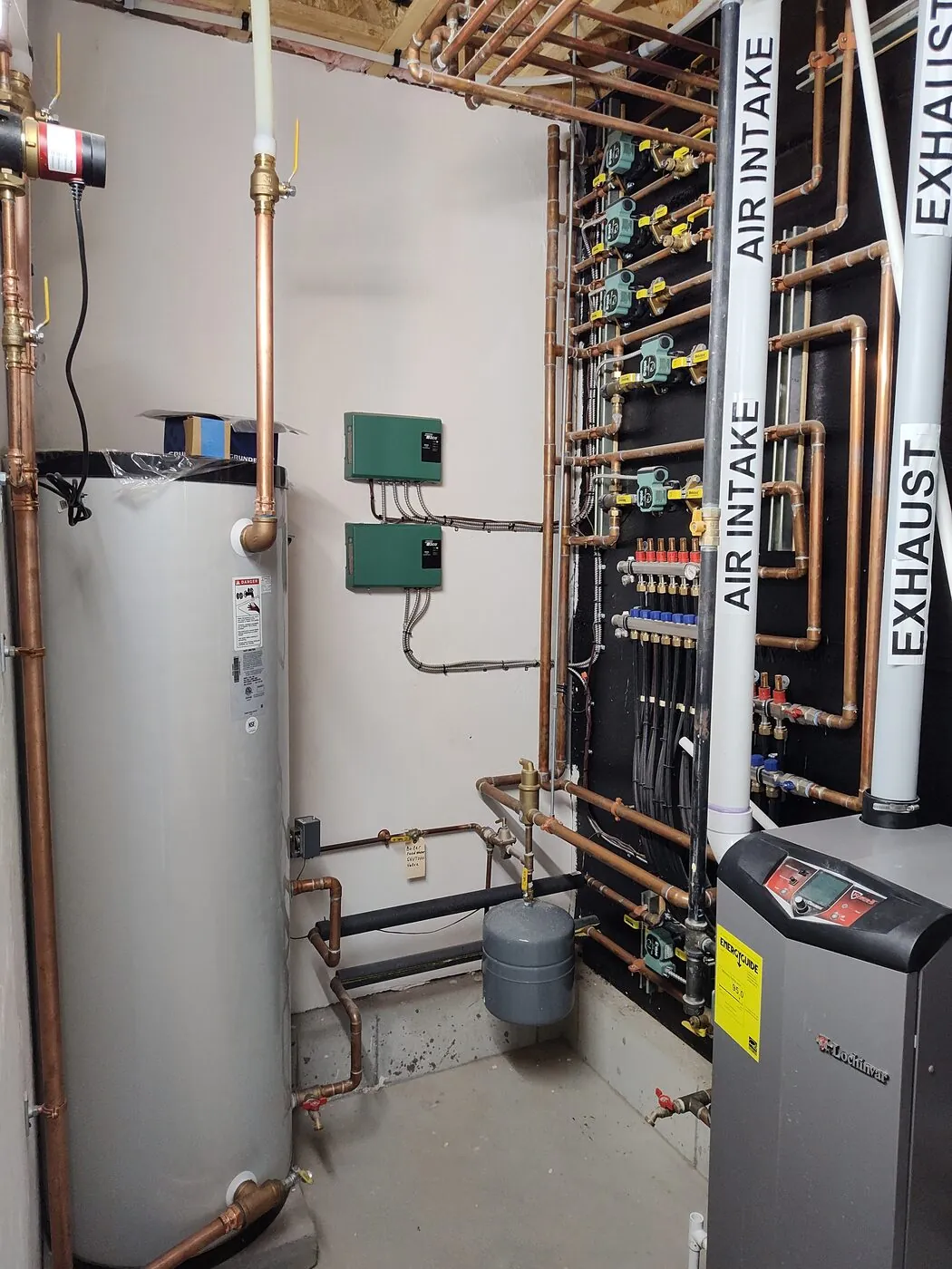 Utility-room water heater and boiler installation with neatly run piping by IS Plumbing