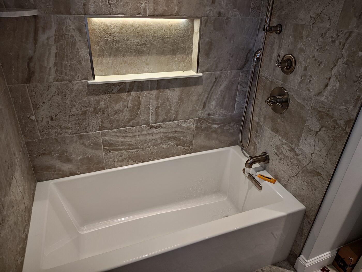 Built-in soaking tub with a marble tile surround and accent lighting