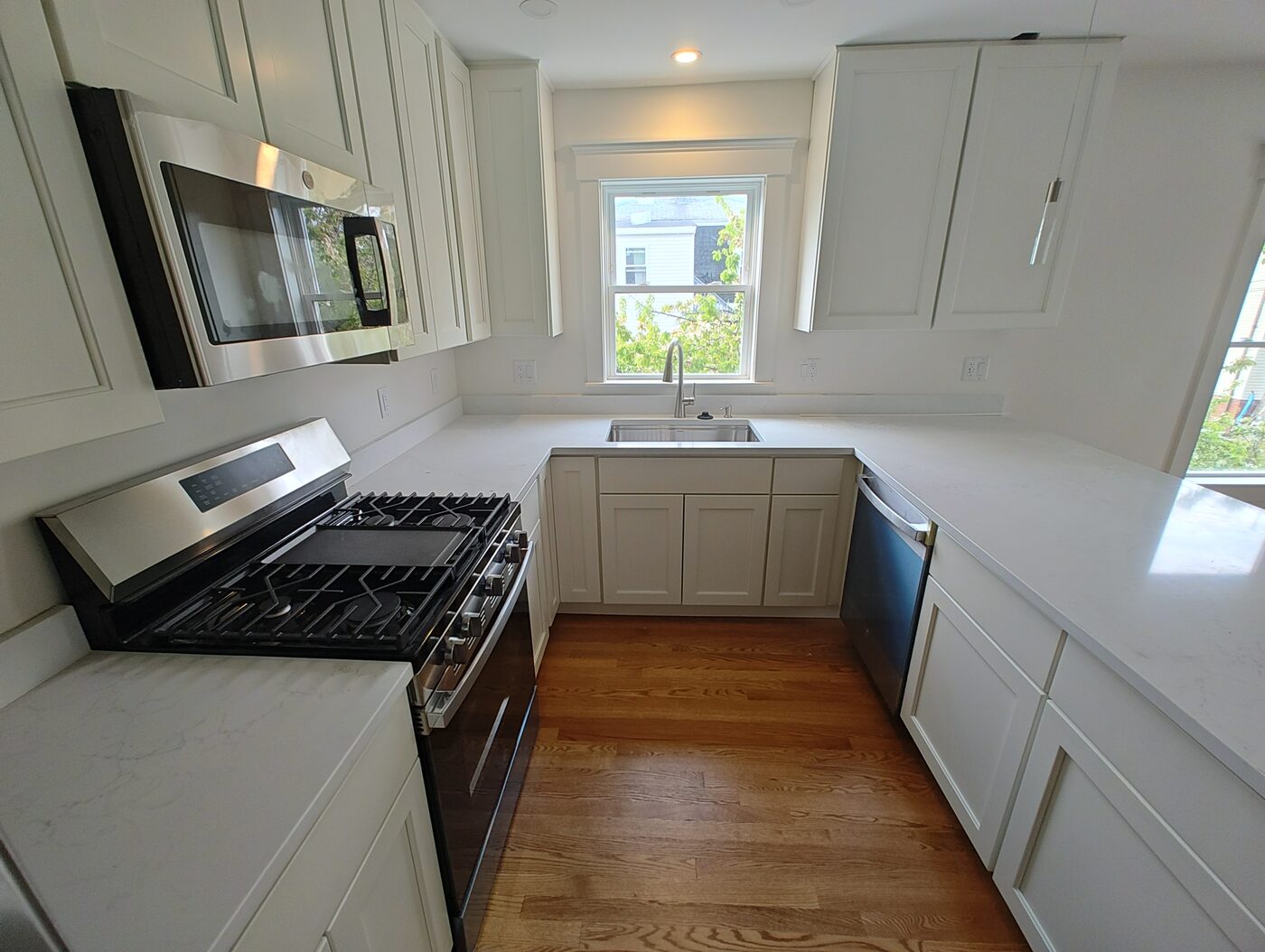 Renovated kitchen with white cabinets, a gas range and hardwood flooring