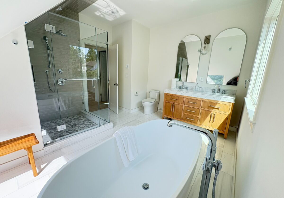 Master bathroom with a frameless glass walk-in shower, freestanding soaking tub and wood double vanity